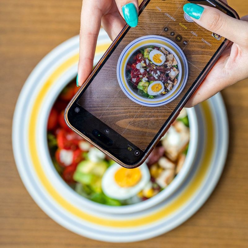Une cliente photographie sa Cobb salad au téléphone