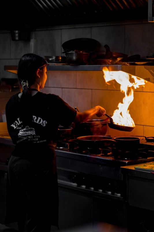 Une cuisinière de Yardbirds flambe une poêle en cuisine