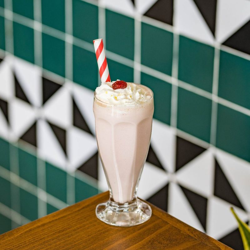 Milkshake à la fraise, crème fouettée et paille rayée
